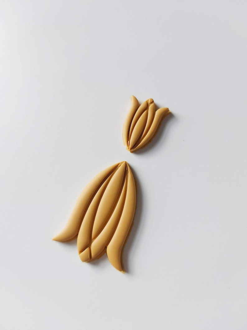 May include: Two yellow clay flower shapes, one is a closed bud and the other is an open flower.
