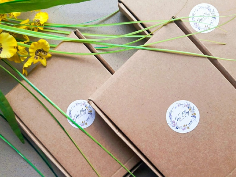 May include: Four brown cardboard boxes with white circular labels that say "Vie Clay" in a floral design. The boxes are stacked on top of each other.