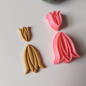 May include: Two sets of tulip-shaped cookie cutters. One set is pink and the other is gold.