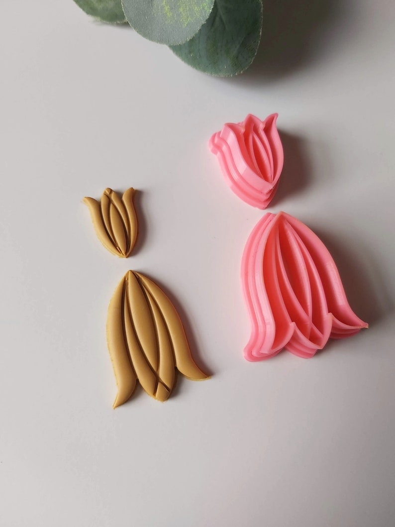 May include: Two sets of tulip-shaped cookie cutters. One set is pink and the other is gold.