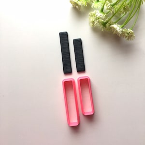 May include: Two black rectangular polymer clay cutters and two pink rectangular polymer clay cutters. The cutters are arranged in two vertical rows.