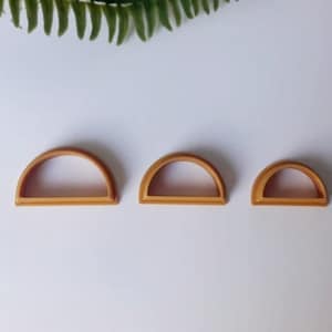 Può includere: Tre tagliabiscotti in plastica a forma di semicerchio di diverse dimensioni, di colore dorato.