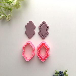 May include: Two sets of cookie cutters, one set is pink and the other is purple. The cutters are shaped like a diamond with rounded edges.