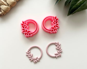 Può includere: Un set di quattro orecchini in resina rosa con un design a corona di foglie. Gli orecchini sono di due dimensioni diverse.