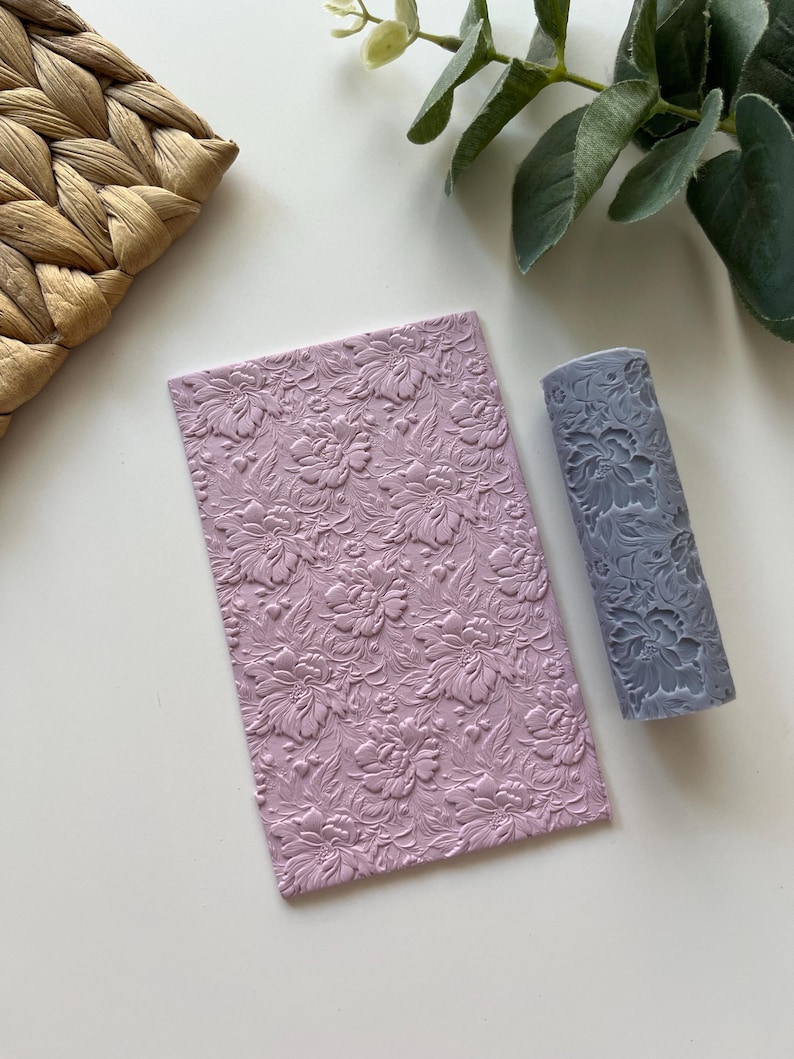 May include: A set of two pink and gray silicone rolling pins with a floral pattern. The rolling pins are used for creating embossed designs on fondant, clay, or dough.