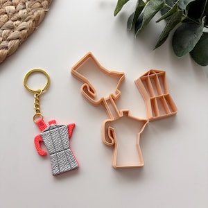 May include: A set of three ceramic mugs with a speckled, matte finish. The mugs are in shades of cream, light gray, and dark gray. Each mug has a simple, minimalist design and a rounded handle.