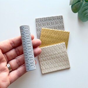 May include: A gray textured roller with a leaf pattern, and three square textured sheets of polymer clay in gray, beige, and yellow with the same leaf pattern.