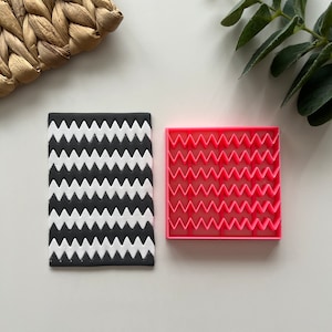 May include: A black and white chevron patterned fondant mold and a pink plastic chevron fondant mold.