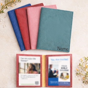 May include: A collection of colorful passport holders in blue, red, pink, and teal. One holder is open, revealing a red interior with printed inserts. The teal holder has the word "Name" printed on it. The holders are made of a textured material.