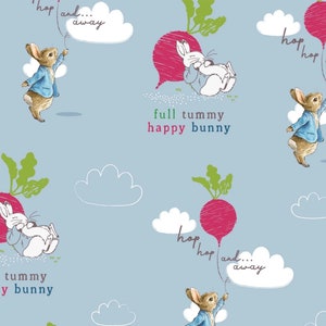 May include: A light blue fabric with a repeating pattern of rabbits, radishes, and clouds. The rabbits are wearing blue jackets and holding balloons. Text includes "hop and... away" and "full tummy happy bunny."