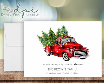 May include: A watercolor illustration of a red pickup truck carrying Christmas trees with colorful lights. The truck has a buffalo plaid pattern. The card includes the text "new season, new home" and family address details.