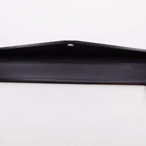 Könnte beinhalten: Ein schwarzer, 3D-gedruckter Telefonständer aus Kunststoff mit einem Loch in der Mitte und zwei Laschen an den Seiten.