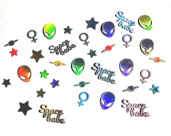 May include: A white background with colorful confetti, including stars, planets, female symbols, and alien heads. The confetti has a holographic finish. The text "Space Babe" appears multiple times in the image.