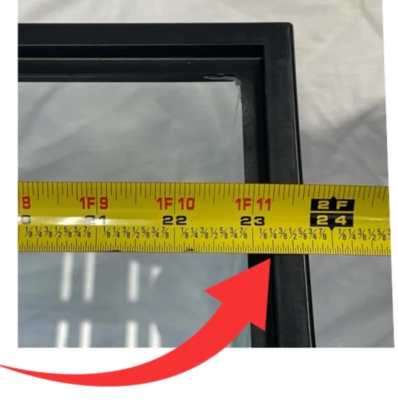 May include: A close-up of a black rectangular frame with a clear glass panel. A yellow measuring tape is placed across the frame, showing a measurement of approximately 24 inches.