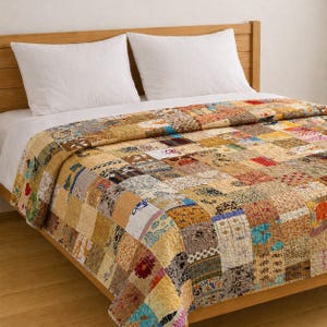 May include: A patchwork quilt with a variety of patterned fabric squares in shades of tan, brown, and cream. The quilt is on a bed with white pillows and a wooden headboard. The quilt's design includes floral and geometric patterns.