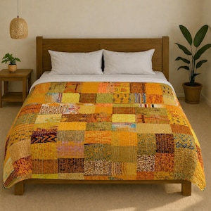 Puede incluir: Una colcha de retazos en tonos amarillos, naranjas y marrones cubre una cama. La colcha está hecha de varios cuadrados de tela con diferentes patrones y texturas. La cama tiene un cabecero de madera y dos almohadas blancas. Se ve una pequeña mesita de noche de madera con una planta y una lámpara colgante de mimbre.