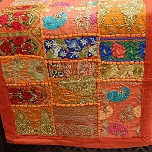 Puede incluir: Un camino de mesa de patchwork colorido con bordados intrincados y detalles de cuentas. El camino de mesa est&aacute; hecho de varias telas en tonos de naranja, rosa, azul y verde. Presenta una variedad de patrones florales y geom&eacute;tricos.