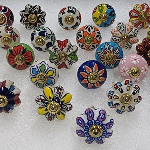 Puede incluir: Surtido de 20 pomos de cajón de cerámica coloridos con diseños florales y geométricos. Cada pomo tiene un acento metálico dorado en el centro.