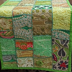 K&ouml;nnte beinhalten: Ein gr&uuml;ner Patchwork-Tischl&auml;ufer mit Stickereien. Der L&auml;ufer besteht aus verschiedenen Stoffen und zeigt eine Vielzahl von Farben, darunter Gr&uuml;n, Gold und Rosa.