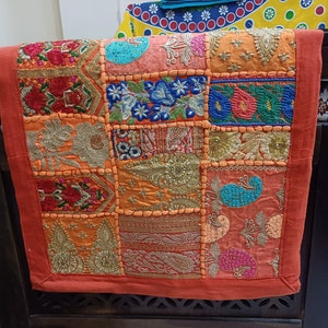 Puede incluir: Un camino de mesa de patchwork colorido con detalles bordados. El camino de mesa est&aacute; hecho de varias telas en tonos de naranja, rojo, azul, verde y dorado. Presenta una variedad de patrones florales y geom&eacute;tricos.