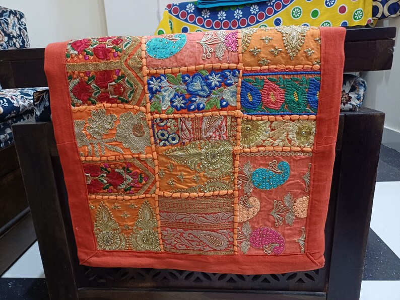 Puede incluir: Un camino de mesa de patchwork colorido con detalles bordados. El camino de mesa est&aacute; hecho de varias telas en tonos de naranja, rojo, azul, verde y dorado. Presenta una variedad de patrones florales y geom&eacute;tricos.