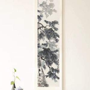 May include: A traditional wooden table with two shelves, a vase with green leaves, and a blue and white teacup on the top shelf. A black and white ink painting of a tree branch with leaves hangs on the wall behind the table.
