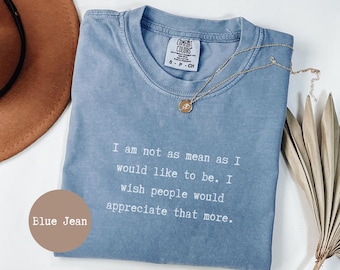 May include: A blue jean coloured t-shirt with the text "I am not as mean as I would like to be. I wish people would appreciate that more." A gold necklace with a pendant is on the shirt.
