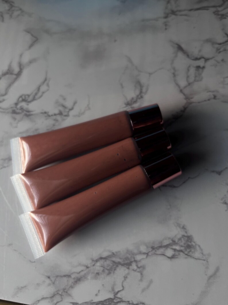 May include: Three tubes of brown lip gloss with clear plastic packaging and gold caps.