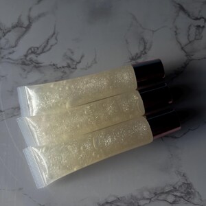 May include: Four clear lip gloss tubes with a shimmery, glittery finish. The tubes have a rose gold cap.