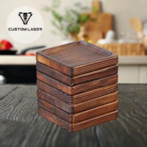 Puede incluir: Una pila de posavasos cuadrados de madera con un borde elevado. Los posavasos son de color marrón cálido y parecen estar hechos de madera texturizada. El logotipo "CUSTOM LASER" está en la esquina superior izquierda. Estos posavasos son ideales para proteger las superficies de las marcas de bebidas.