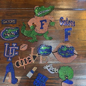 May include: A collection of beaded patches and appliqués, including a green alligator mascot wearing an orange shirt with a blue "F", "Gators" text, a blue high heel, and the word "Love".