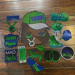 Puede incluir: Una colección de accesorios con temática de Tauro con incrustaciones de pedrería, que incluyen una gorra de béisbol, labios, un tacón alto y un teléfono. La combinación de colores es principalmente verde, azul y plateado, con la palabra "Tauro" en varios artículos.