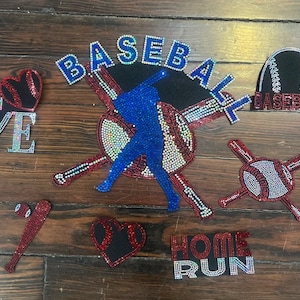 Könnte beinhalten: Eine Sammlung von Baseball-Themen-Strassverzierungen. Das Bild zeigt das Wort "BASEBALL" in blauen Strasssteinen, einen Baseballspieler, einen Baseball, einen Schläger und die Wörter "LOVE" und "HOME RUN". Die Verzierungen sind rot, weiß und blau.