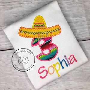 May include: A white t-shirt with a colorful embroidered sombrero, the number 3 with a striped pattern, and the name "Sophia" in rainbow colors.
