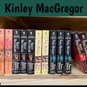 May include: A shelf of paperback books by author Kinley MacGregor. The books are all historical romance novels with titles like "A Dark Champion", "Knight of Darkness", and "Return of the Warrior".