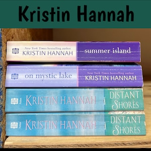 K&ouml;nnte beinhalten: Vier B&uuml;cher von Kristin Hannah sind auf einem Holzregal gestapelt. Zu den Titeln geh&ouml;ren "Summer Island", "On Mystic Lake" und zwei Exemplare von "Distant Shores". Die B&uuml;cher haben farbenfrohe Einb&auml;nde in Lila- und Blaut&ouml;nen.
