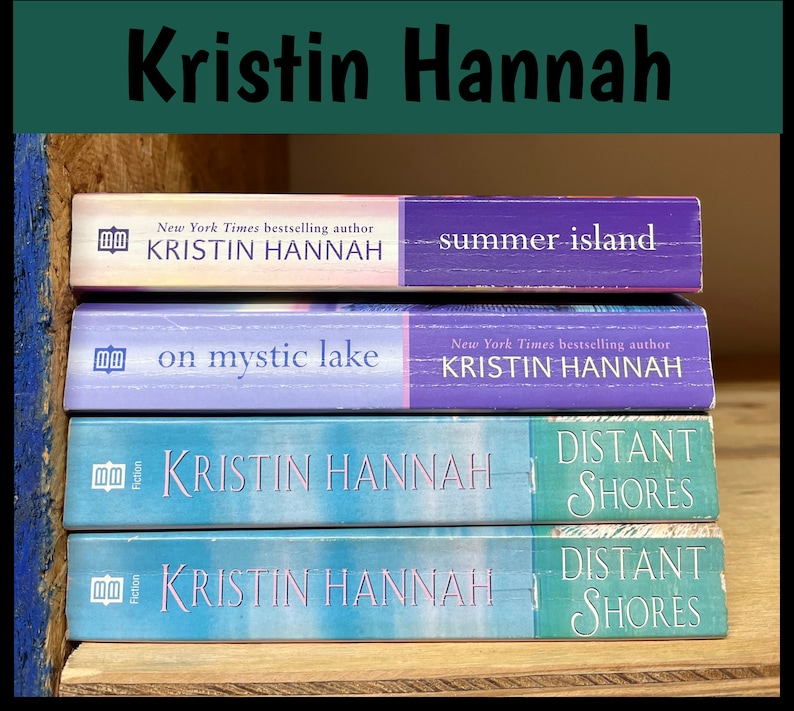 K&ouml;nnte beinhalten: Vier B&uuml;cher von Kristin Hannah sind auf einem Holzregal gestapelt. Zu den Titeln geh&ouml;ren "Summer Island", "On Mystic Lake" und zwei Exemplare von "Distant Shores". Die B&uuml;cher haben farbenfrohe Einb&auml;nde in Lila- und Blaut&ouml;nen.