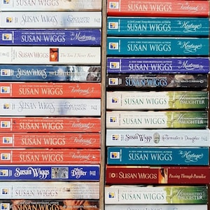 May include: A collection of paperback books by author Susan Wiggs. The books are stacked vertically in two columns. The books have various titles, including "The Hostage", "Firebrand", "Mistress", "Charm School", and "The Drifter".