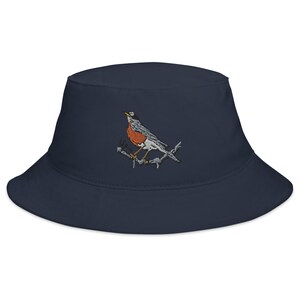 Op de afbeelding: Marineblauwe vissershoed met een borduursel van een roodborstje op een tak. De vogel heeft oranje, grijze en witte details. De hoed is een casual accessoire, geschikt voor diverse buitenactiviteiten.