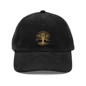 Puede incluir: Una gorra de béisbol de pana negra con un diseño de árbol de la vida bordado en oro.
