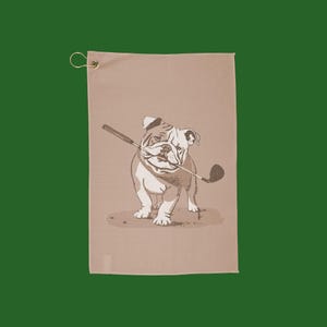 May include: A tan golf towel featuring a brown bulldog illustration holding a golf club in its mouth.