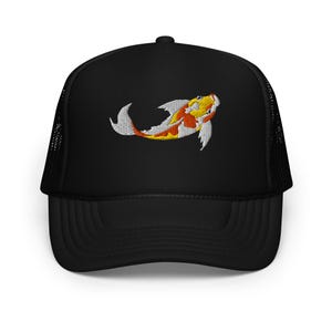 May include: Black trucker hat featuring an embroidered koi fish design. The koi fish is in shades of yellow, orange, and white. The hat has a mesh back and a curved brim.