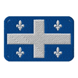May include: A blue embroidered patch featuring a white cross and four white fleur-de-lis symbols. The patch has a rectangular shape with rounded corners and a stitched border, resembling a flag or emblem.