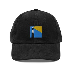 Può includere: Cappellino da baseball in velluto a coste nero con una toppa ricamata raffigurante un faro. Il faro è bianco e nero, su uno sfondo blu e giallo. Il cappellino ha una visiera curva e un bottone sulla parte superiore.