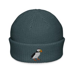 May include: A dark blue knitted beanie with a white embroidered puffin design.