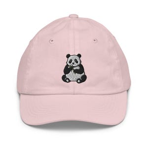 Può includere: Un berretto da baseball rosa con un panda nero e bianco ricamato che tiene un pezzo di bambù.