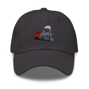 May include: A charcoal gray baseball cap featuring an embroidered train design. The train is detailed in gray and white, with a red caboose. The cap has a curved brim and a structured fit, suitable for casual wear.