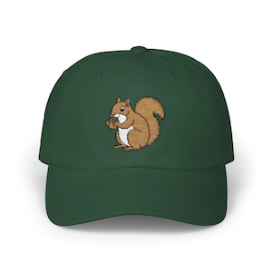 May include: A dark green baseball cap with an embroidered image of a brown squirrel holding a nut.