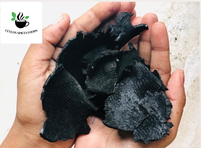 Puede incluir: Primer plano de un pu&ntilde;ado de trozos de carb&oacute;n vegetal negro. El carb&oacute;n vegetal est&aacute; roto en formas y tama&ntilde;os irregulares.