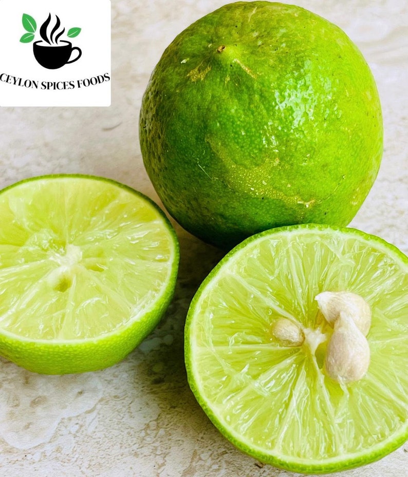 Puede incluir: Tres limas verdes, una entera y dos mitades, se muestran sobre una superficie clara. Las limas cortadas revelan el interior jugoso y las semillas. La imagen incluye el texto "CEYLON SPICES FOODS" con un logotipo de una taza y hojas.